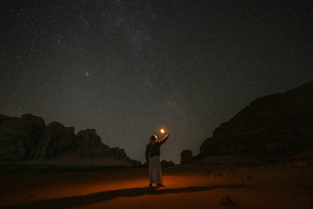 a person standing in the desert holding a lantern